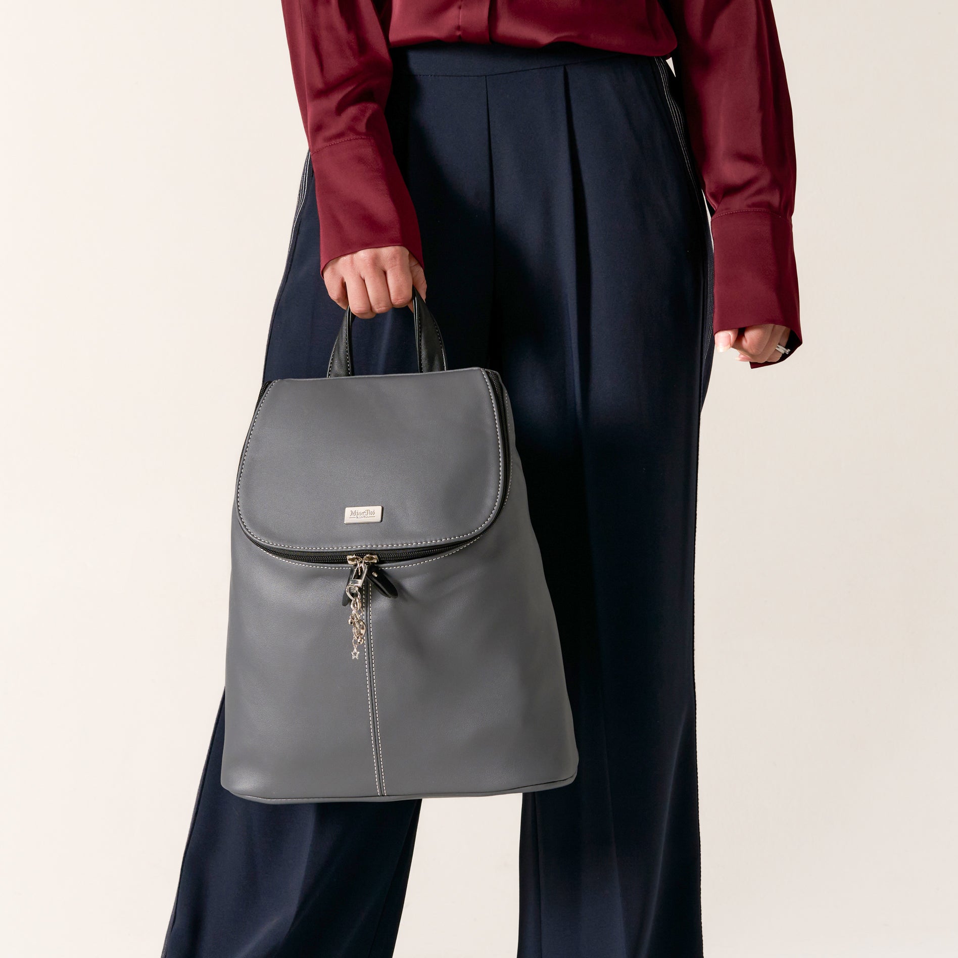 Woman in stylish outfit holding a Graphite handbag, showcasing modern fashion and elegance.