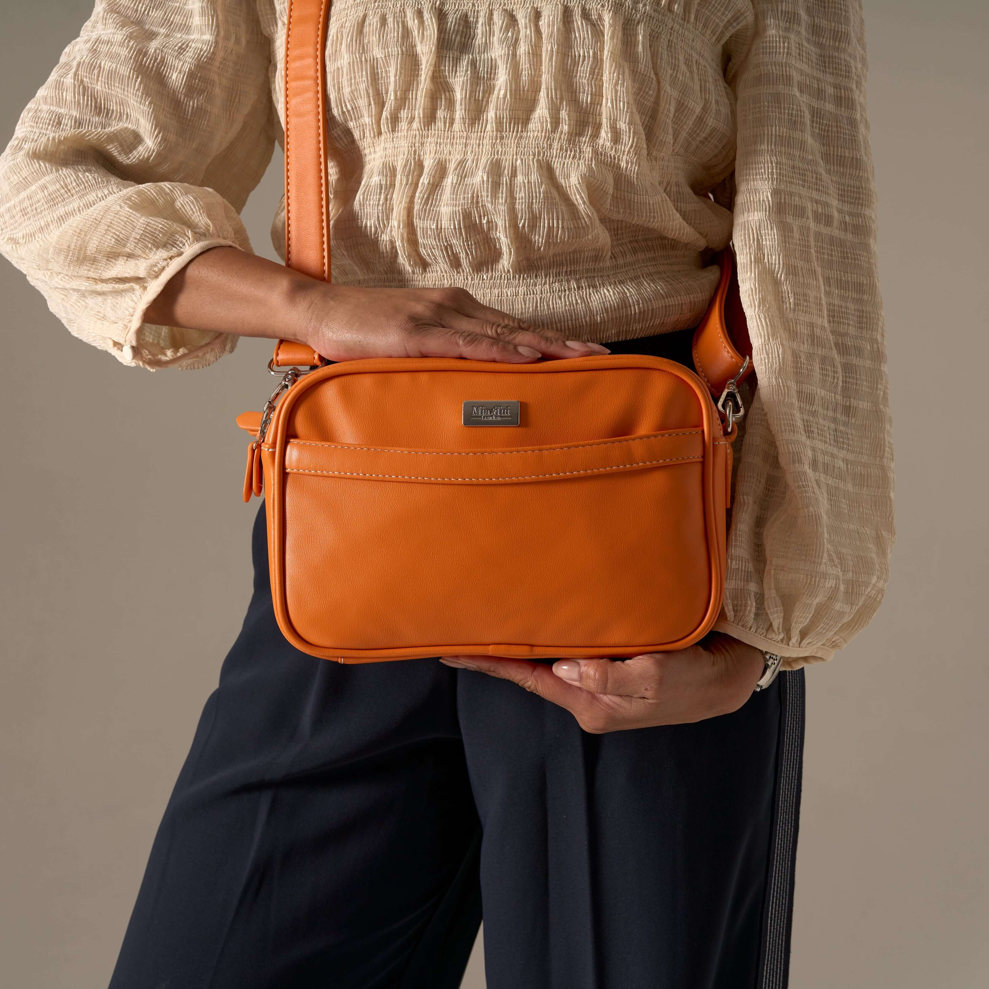 Model showcasing a stylish orange handbag from the Tangerine collection, perfect for all occasions.