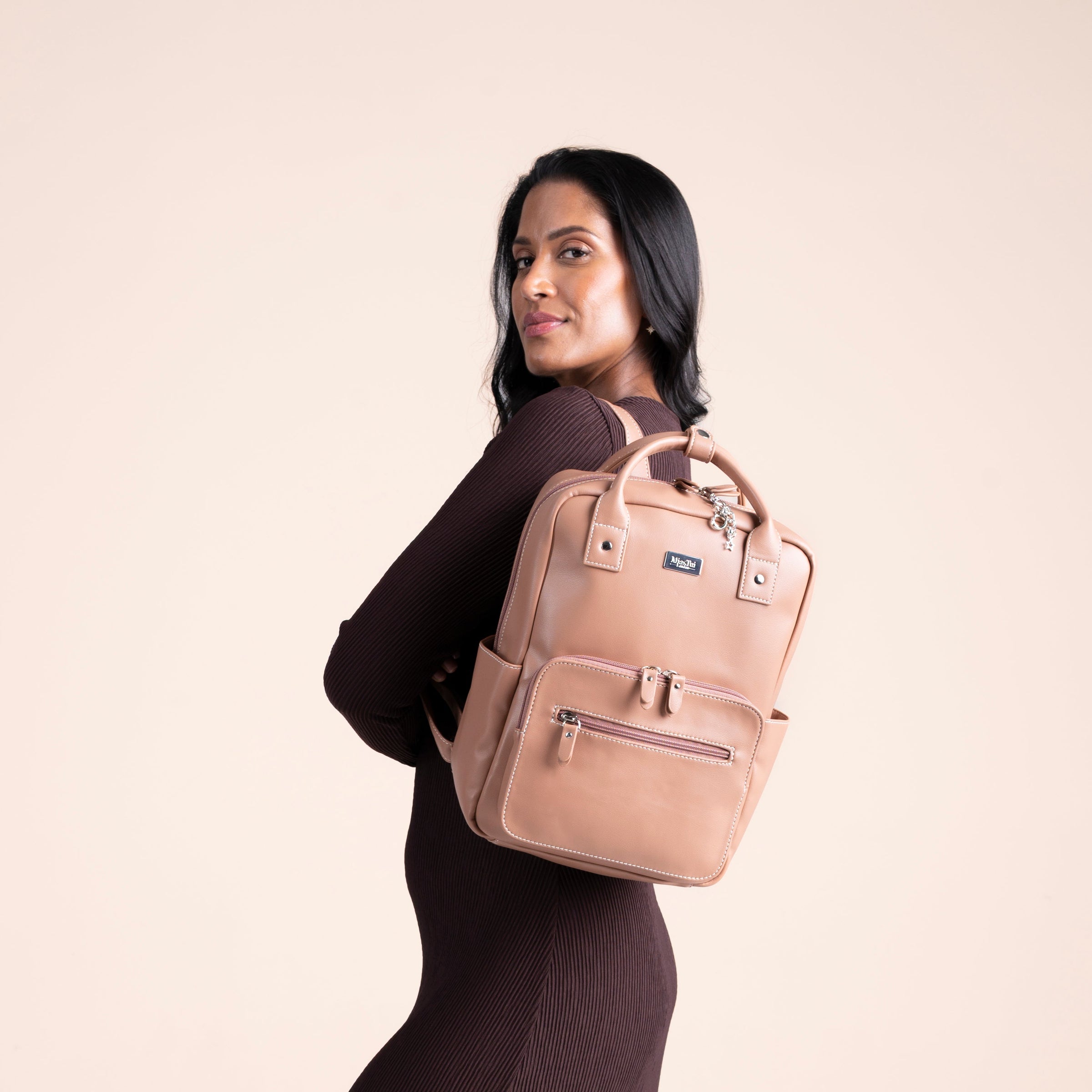Oyster collection handbag in light beige style held by model with long hair and elegant outfit.