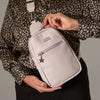 Person holding a Large Emma Sling Bag in beige, showcasing its front pocket and ergonomic design for hands-free convenience.