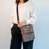 Person holding O'Grady Dog Bag - Outlet in leopard print, featuring a water-resistant design for practical dog walking essentials.